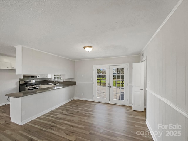 kitchen featuring dark countertops, french doors, a peninsula, stainless steel gas range, and a sink