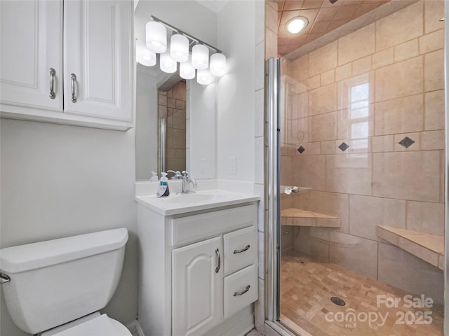 bathroom featuring a shower stall, toilet, and vanity