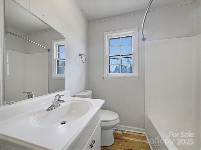 full bathroom with visible vents, shower / washtub combination, toilet, wood finished floors, and vanity