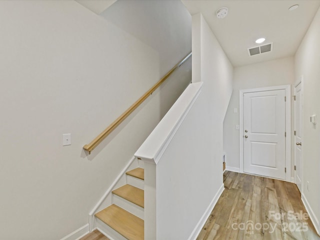 staircase featuring visible vents, baseboards, and wood finished floors