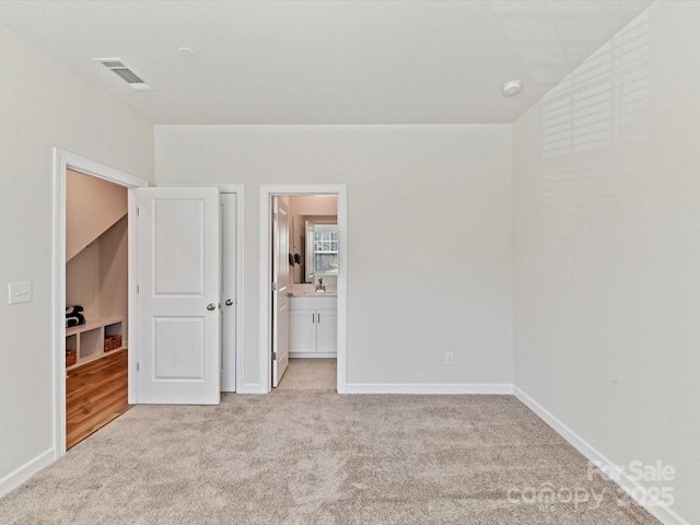 unfurnished bedroom with visible vents, baseboards, light colored carpet, and connected bathroom