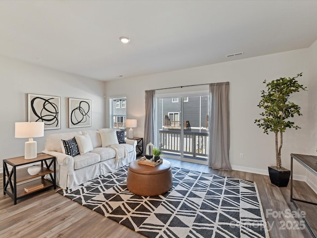 living room featuring visible vents, baseboards, and wood finished floors