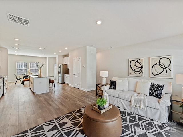 living area featuring visible vents, recessed lighting, light wood-type flooring, and baseboards