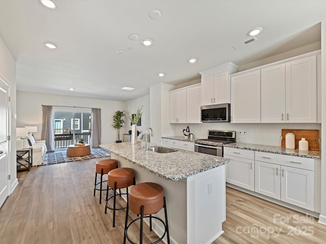 kitchen with visible vents, appliances with stainless steel finishes, light wood-style floors, and a sink