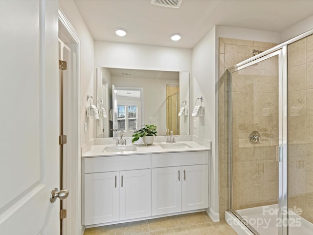 full bath with double vanity, a stall shower, and a sink