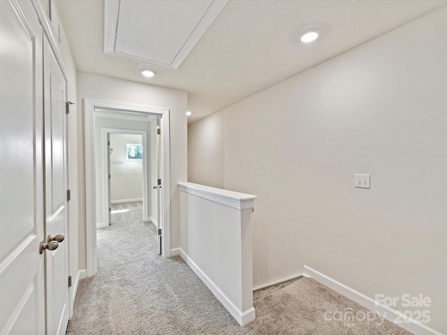 corridor with baseboards, an upstairs landing, light carpet, and attic access