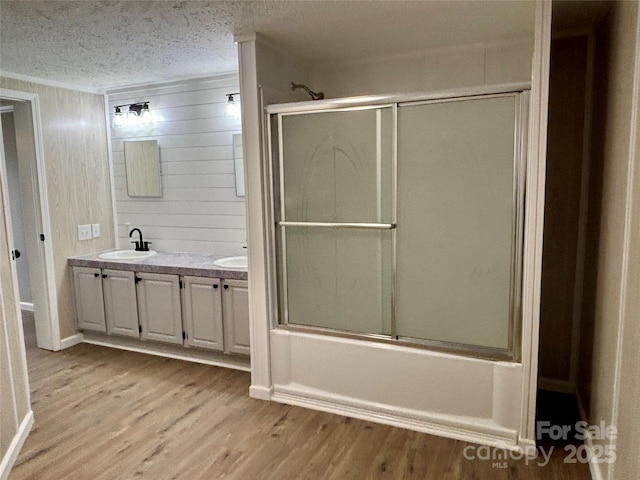 full bath featuring crown molding, double vanity, wood finished floors, a textured ceiling, and a sink