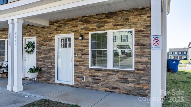 property entrance featuring stone siding and a porch