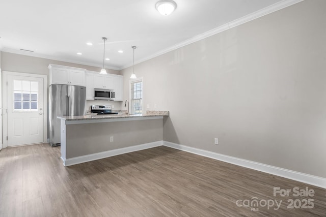 kitchen featuring baseboards, ornamental molding, appliances with stainless steel finishes, wood finished floors, and white cabinets