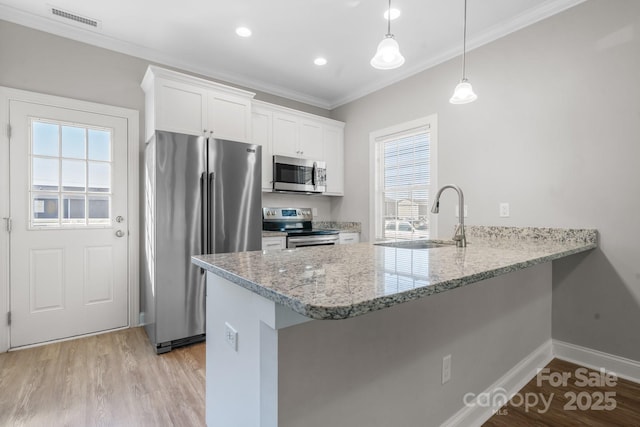 kitchen with visible vents, a sink, stainless steel appliances, a peninsula, and light wood finished floors