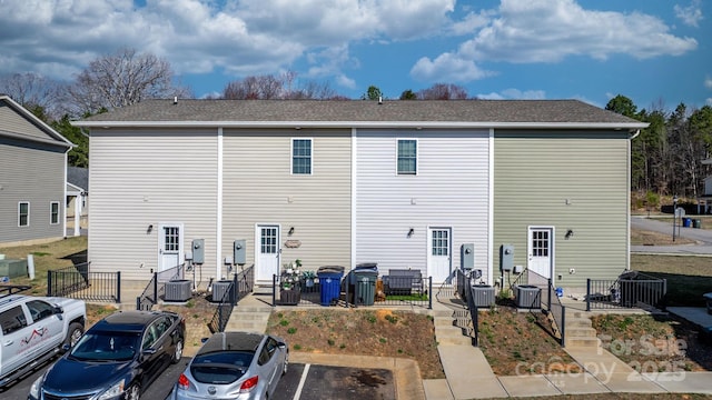 back of house featuring central AC unit and uncovered parking