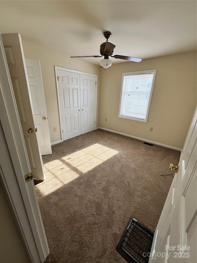 unfurnished bedroom featuring a closet, carpet flooring, baseboards, and visible vents