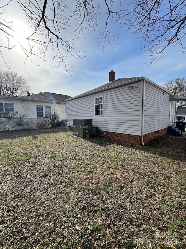 back of house featuring cooling unit, fence, a yard, and a chimney