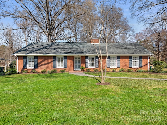 ranch-style house featuring brick siding, a chimney, a front lawn, and a shingled roof