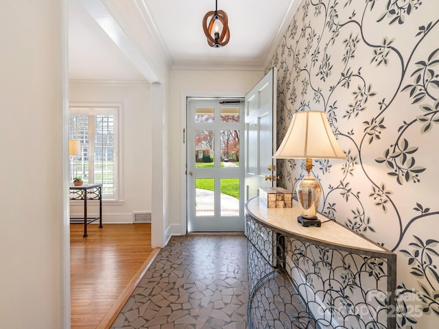 entrance foyer with visible vents, baseboards, wallpapered walls, stone finish flooring, and crown molding