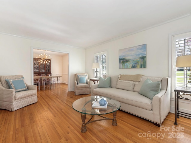 living room featuring light wood-style floors, a chandelier, and ornamental molding