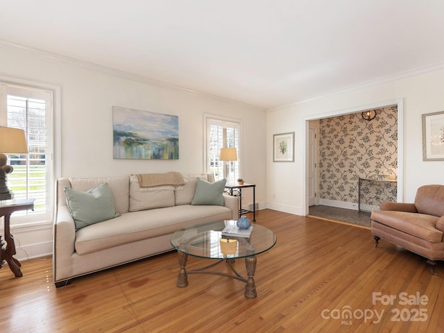 living room featuring light wood-type flooring, baseboards, and ornamental molding