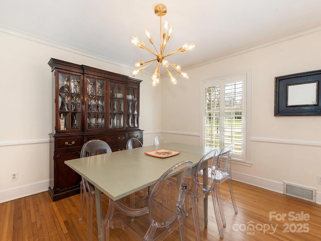 dining room with visible vents, baseboards, ornamental molding, an inviting chandelier, and light wood-style floors