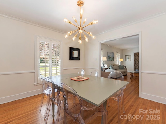 dining area featuring a notable chandelier, crown molding, light wood-type flooring, and baseboards