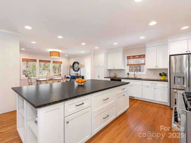 kitchen with a healthy amount of sunlight, light wood finished floors, open shelves, a sink, and appliances with stainless steel finishes