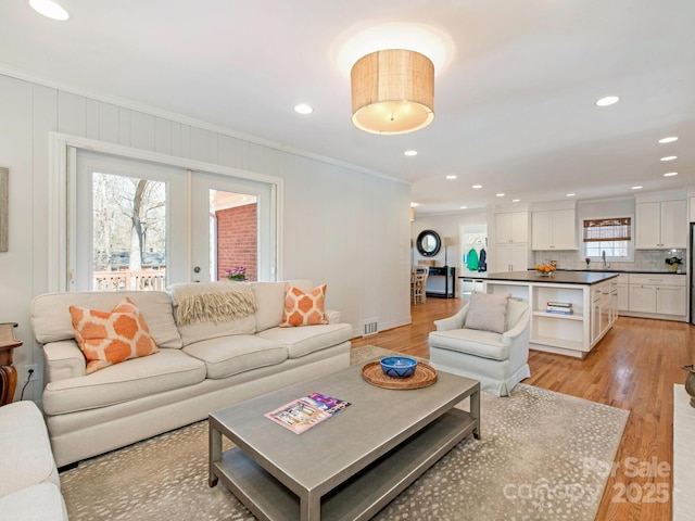 living area featuring crown molding, recessed lighting, visible vents, and light wood finished floors