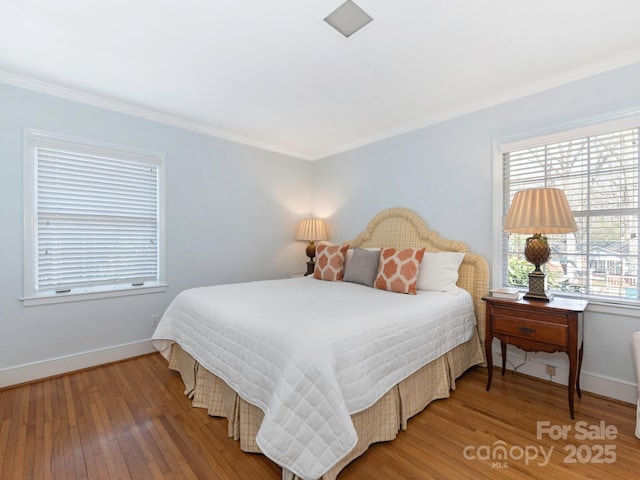 bedroom with baseboards, crown molding, and hardwood / wood-style flooring