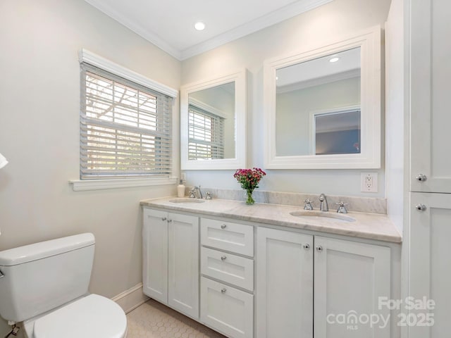 bathroom with double vanity, toilet, crown molding, and a sink