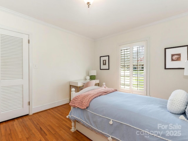 bedroom with crown molding, wood finished floors, and baseboards