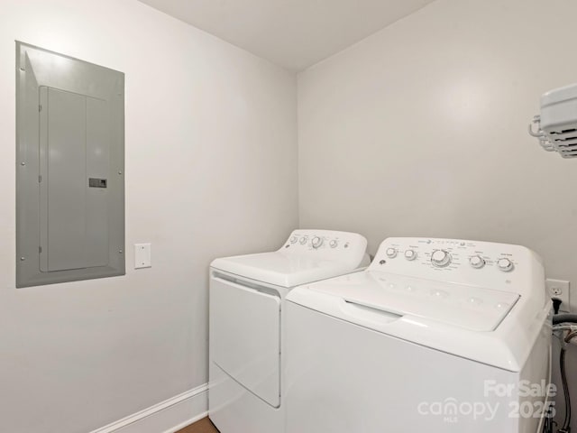 clothes washing area with electric panel, laundry area, washing machine and dryer, and baseboards