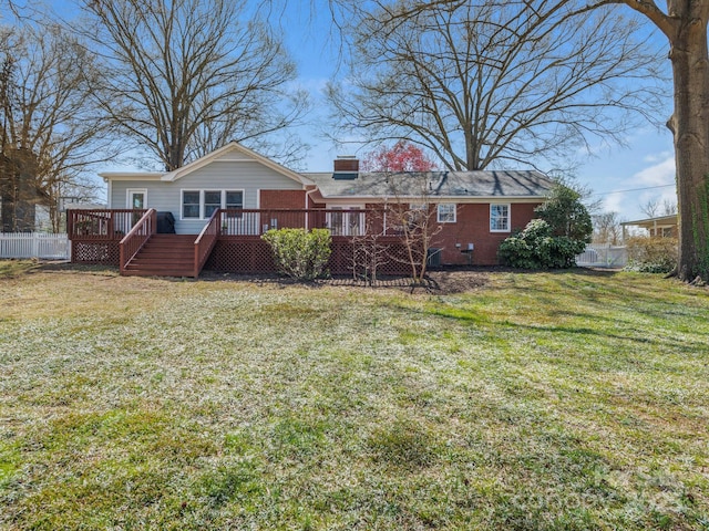 back of property featuring a yard, brick siding, a wooden deck, and fence