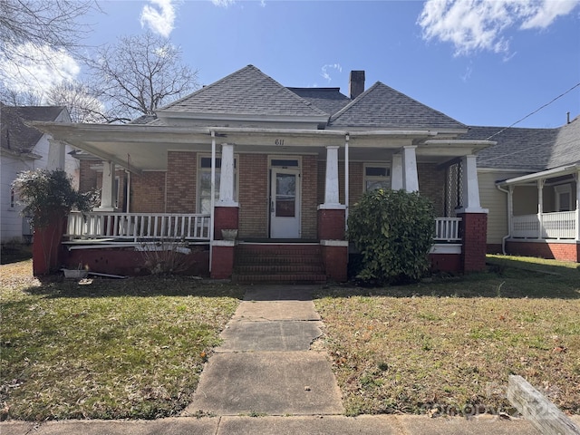 bungalow featuring brick siding, covered porch, and a front lawn