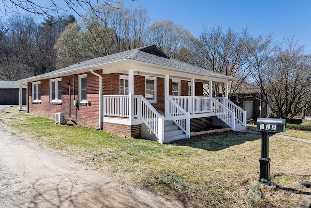 view of side of property with brick siding, a shingled roof, central air condition unit, a porch, and a lawn