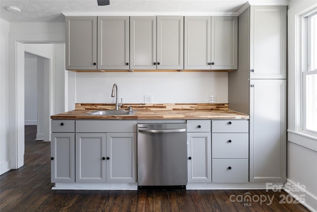 kitchen featuring dark wood-style floors, gray cabinetry, a sink, stainless steel dishwasher, and butcher block counters