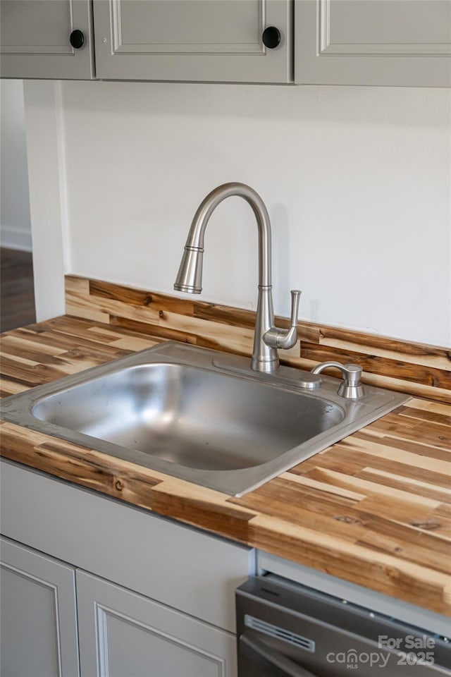 room details featuring black dishwasher, gray cabinets, wooden counters, and a sink