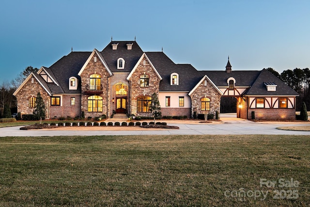 french country style house with concrete driveway and a front lawn