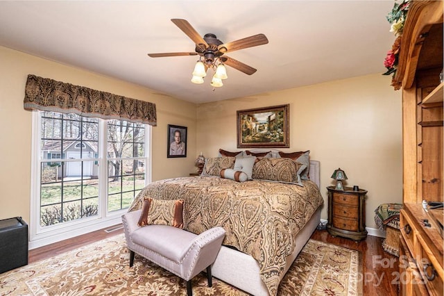 bedroom with ceiling fan, wood finished floors, visible vents, and baseboards