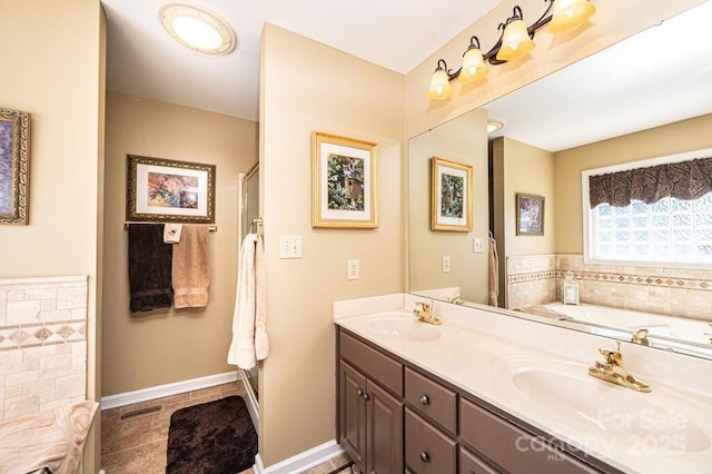 full bath featuring double vanity, a bath, baseboards, and a sink