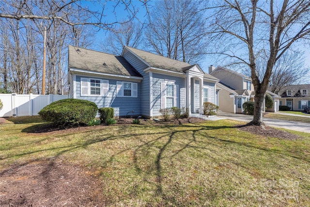 view of front facade featuring a front lawn, concrete driveway, and fence