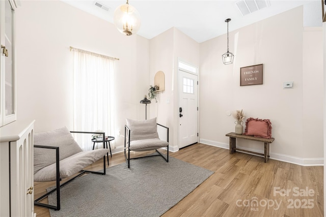 foyer with baseboards, visible vents, and light wood-type flooring