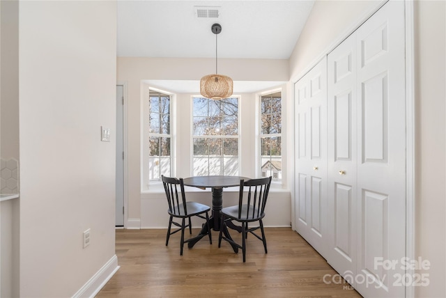 dining area with visible vents, light wood-style flooring, and baseboards