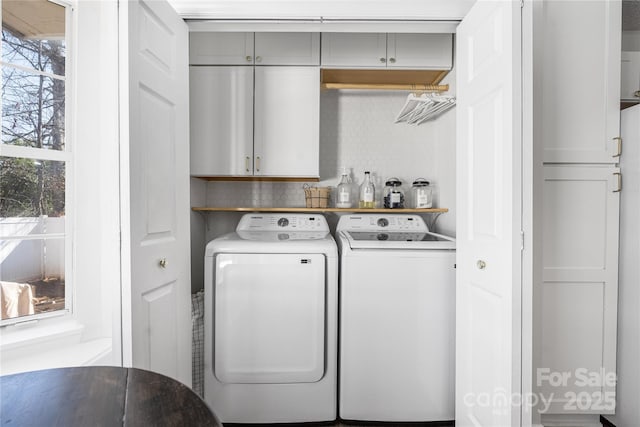 washroom featuring cabinet space and washer and clothes dryer