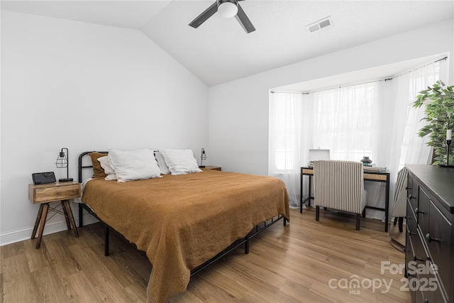 bedroom with visible vents, light wood-style flooring, a ceiling fan, radiator, and vaulted ceiling