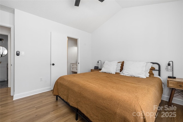 bedroom with ceiling fan, wood finished floors, baseboards, and vaulted ceiling