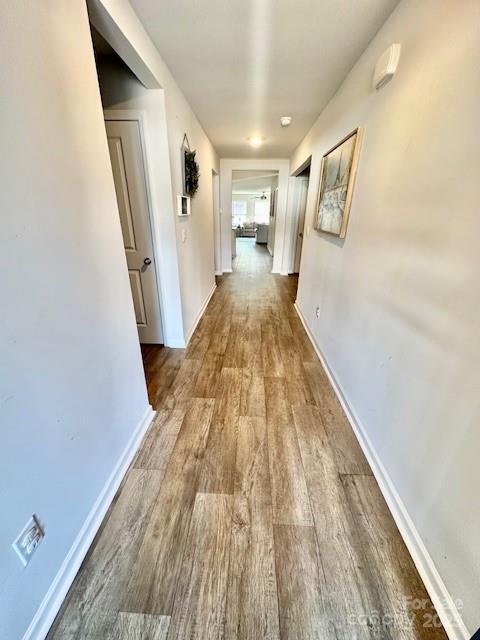 corridor with baseboards and wood finished floors