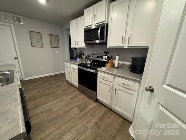 kitchen featuring visible vents, appliances with stainless steel finishes, white cabinetry, and a sink