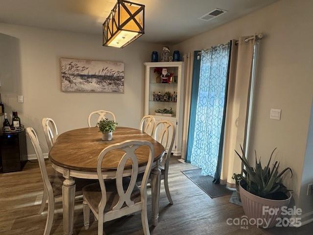 dining space with wood finished floors, visible vents, and baseboards