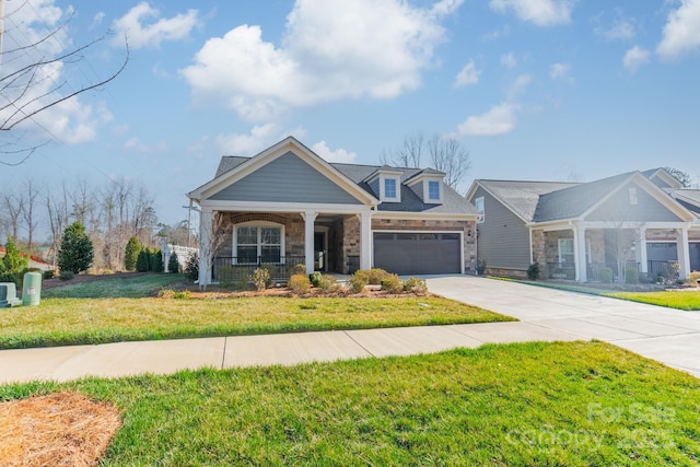 view of front facade with a front yard, a porch, concrete driveway, a garage, and stone siding