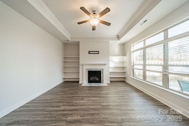 unfurnished living room featuring a tray ceiling, baseboards, dark wood-style floors, and crown molding