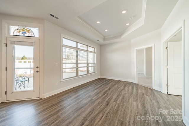 foyer with visible vents, ornamental molding, a raised ceiling, and wood finished floors