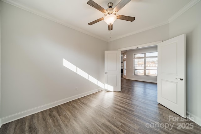 unfurnished room featuring a ceiling fan, dark wood-style floors, baseboards, and ornamental molding